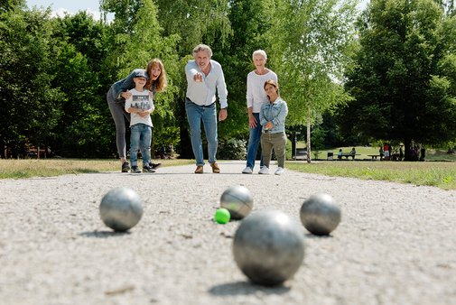 Boulespiel KInder und Erwachsene auf einer Boule-Bahn beim gemeinsamen Spiel.